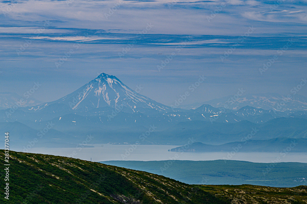 Fototapeta premium Panoramic view of the city Petropavlovsk-Kamchatsky and volcanoes: Koryaksky Volcano, Avacha Volcano, Kozelsky Volcano. Russian Far East, Kamchatka Peninsula.
