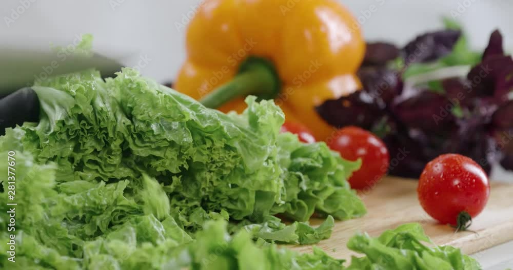 Chef cuts the salad leaves with a knife in slow motion, making a salad, fresh vegetables on a cutting board. Chef cuts the salad leaves with a knife in slow motion, making a salad, fresh vegetables on a cutting board.