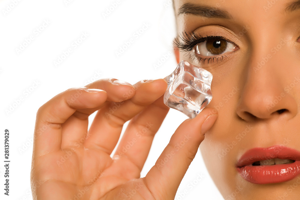 young beautiful woman holding ice cube under the eye on white background young beautiful woman holding ice cube under the eye on white background