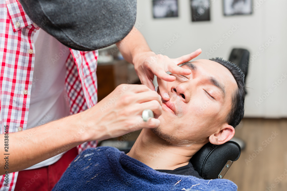 Fototapeta premium Professional barber shaving with razor