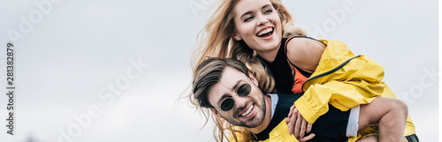 panoramic shot of attractive and blonde woman and handsome man hugging and playing on roof
