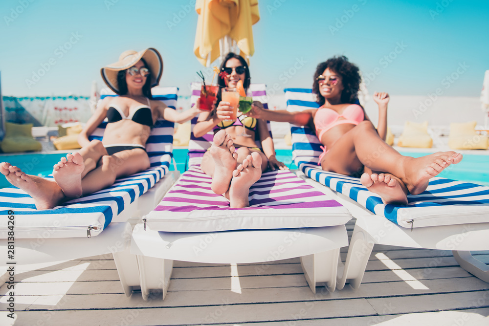 Nice attractive glamorous cheerful cheery slim thin fit girls lying on sunbed at modern fashionable spa resort hotel country club roof top having fun clinking glasses cold lemonade bachelorette - obrazy, fototapety, plakaty 