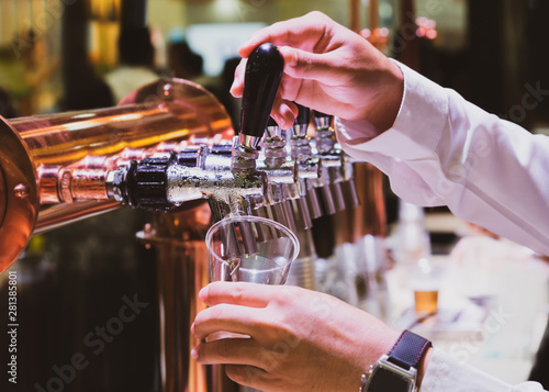 Bartender pouring draft beer in the bar, Barman hand at beer tap pouring draught lager beer serving in a restaurant or pub