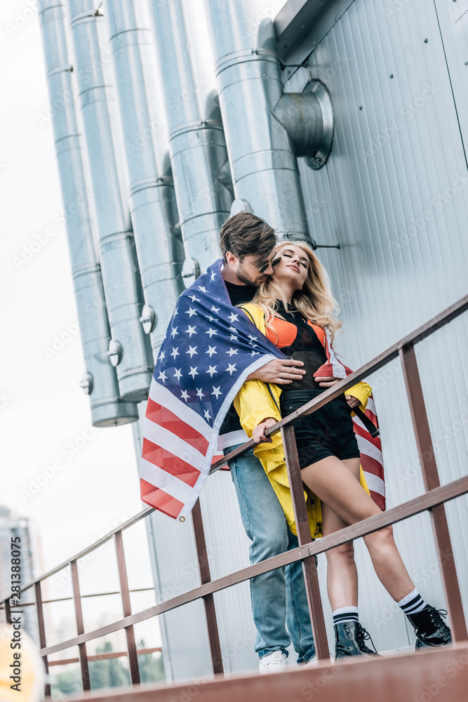 attractive woman and handsome man with american flag hugging on roof