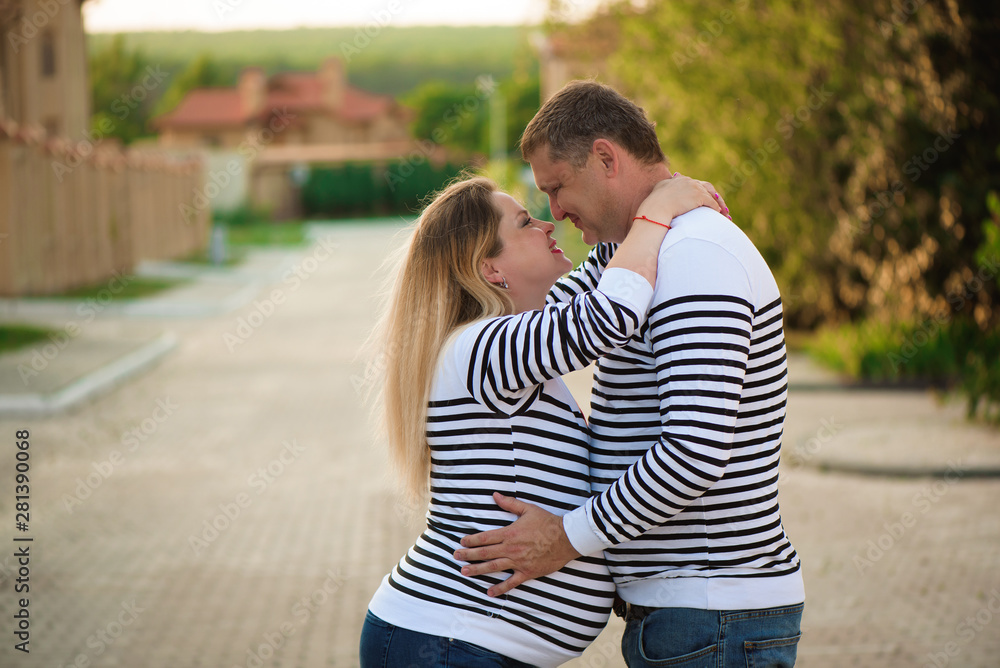 Fototapeta premium Happy pregnant woman and her husband kissing and hugging, posing on the street.