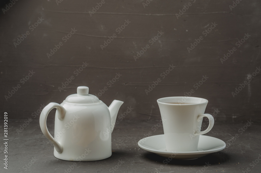 Tea cup and teapot on on dark stone table. Selective focus