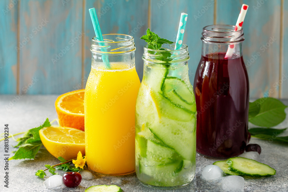 Various refreshments drinks - detox cucumber water, cherry juice and orange juice on stone table. Various refreshments drinks - detox cucumber water, cherry juice and orange juice on stone table.