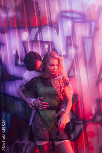 attractive and blonde woman hugging with handsome man in night club