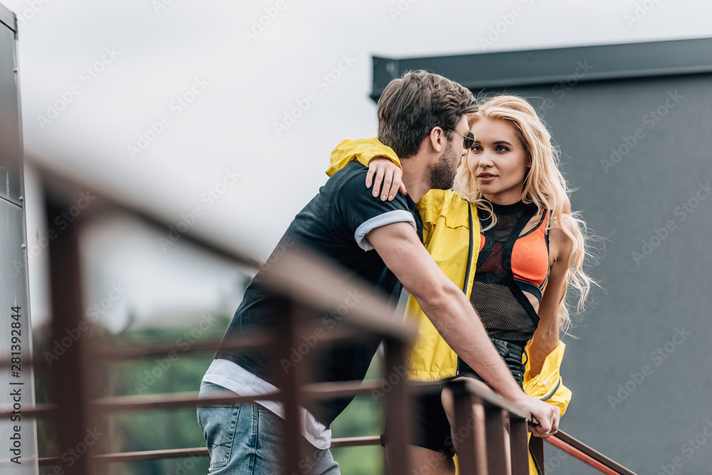 blonde woman and handsome man hugging and looking at each other on roof