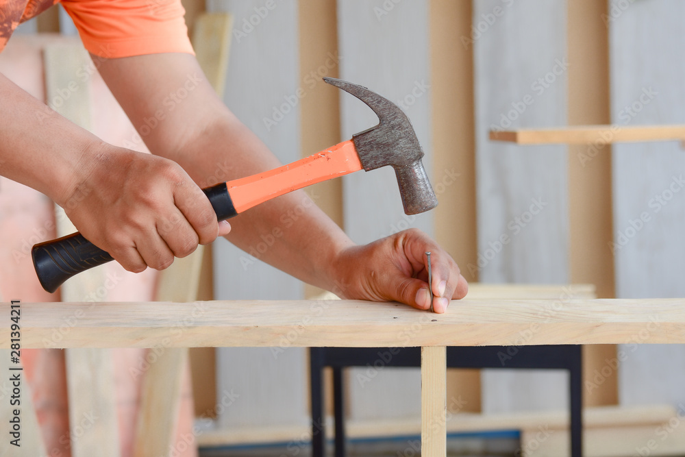 carpenter using the hammer hit a nail for assembly wood. Stock Photo |  Adobe Stock