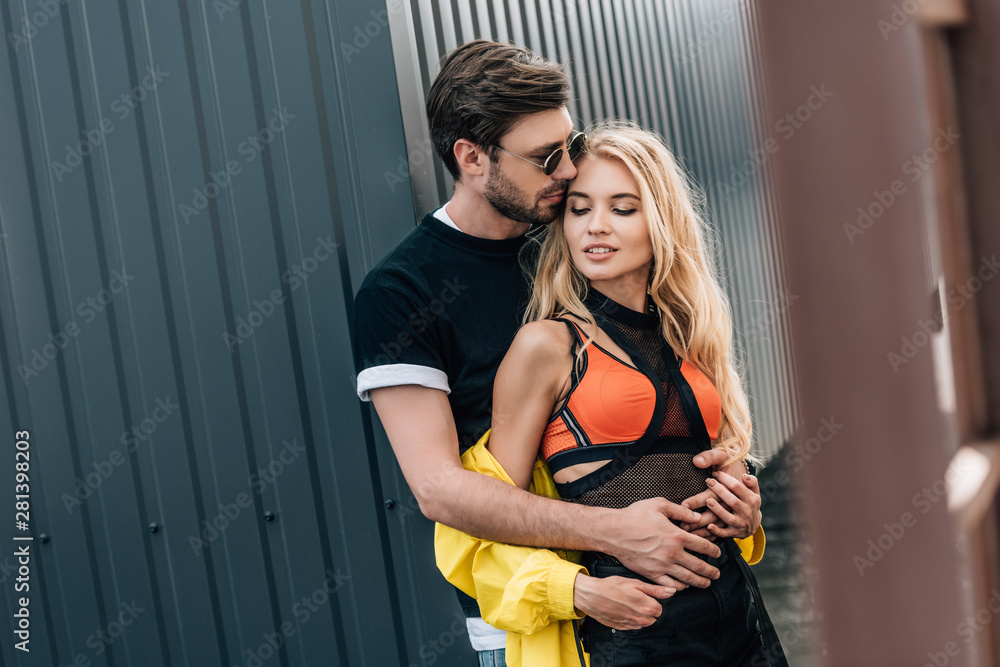 Naklejka premium attractive woman and handsome man in glasses hugging on roof