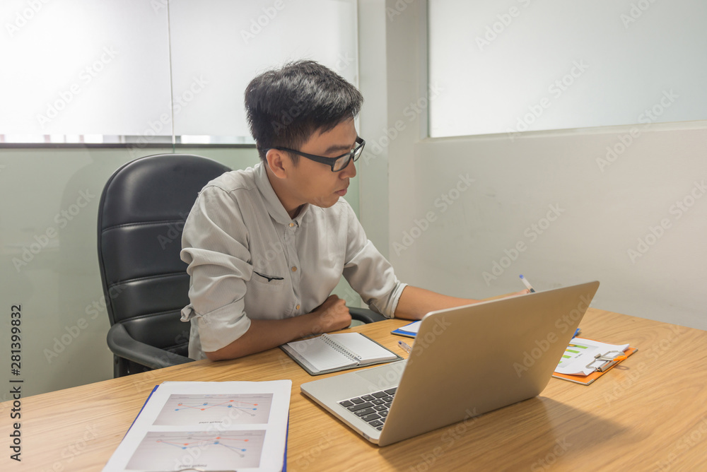 Young Asian supervisor working on laptop and statistic documents Young Asian supervisor working on laptop and statistic documents