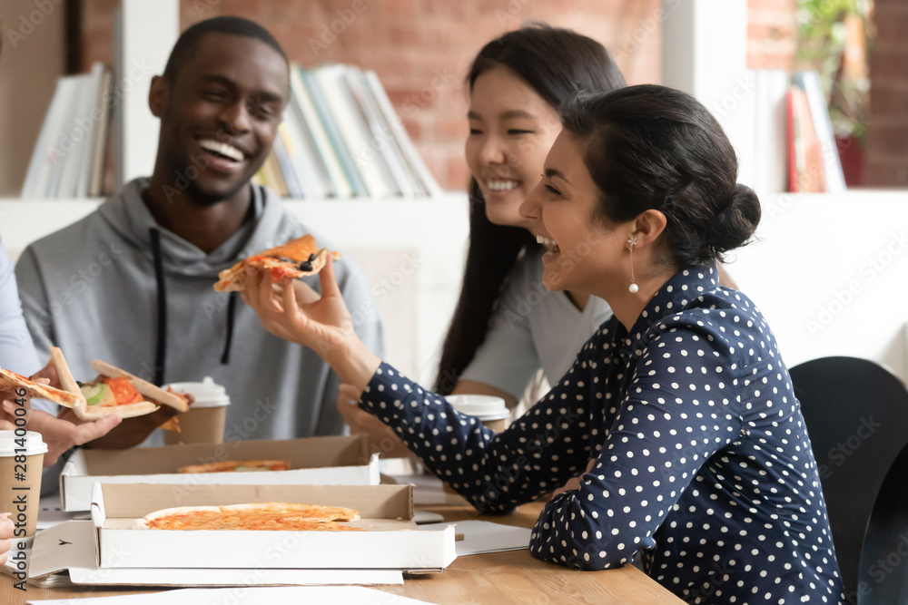 Happy multiracial young people have fun eating pizza