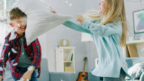 Canvas Print Adorable Little Boy and Sweet Little Girl Have a Pillow Fight in the Sunny Living Room