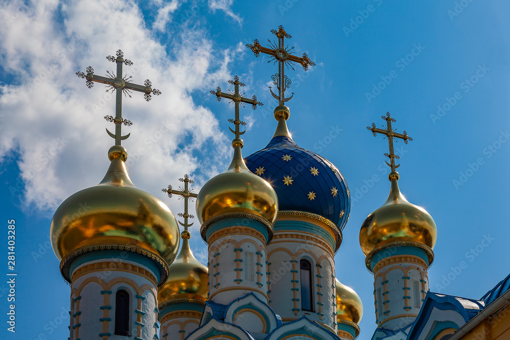 Blue and golden domes of an orthodox temple against a cloudy sky