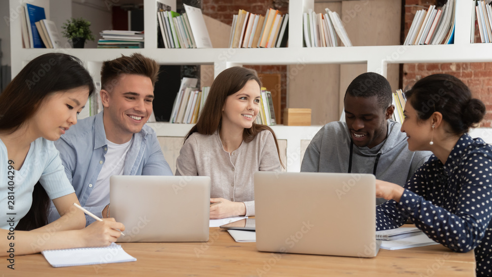 Smiling diverse students talk studying in library together Smiling diverse students talk studying in library together