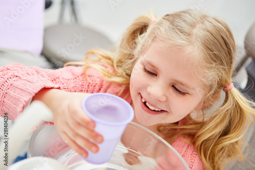 Mädchen beim Zahnarzt mit einem Becher Wasser