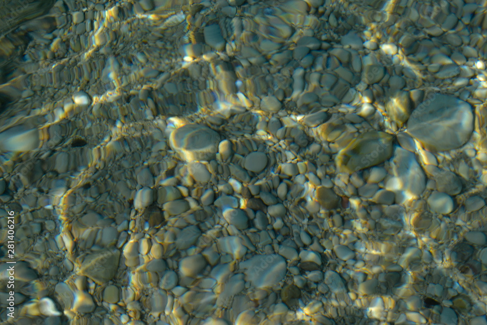 Top view of blue, green and turquoise colors of water, surface of sea on rocks and bottom. Reflection of sun beams in water, shallow soil, shoal of ocean. Sea texture, background, pattern, wallpaper. Top view of blue, green and turquoise colors of water, surface of sea on rocks and bottom. Reflection of sun beams in water, shallow soil, shoal of ocean. Sea texture, background, pattern, wallpaper.
