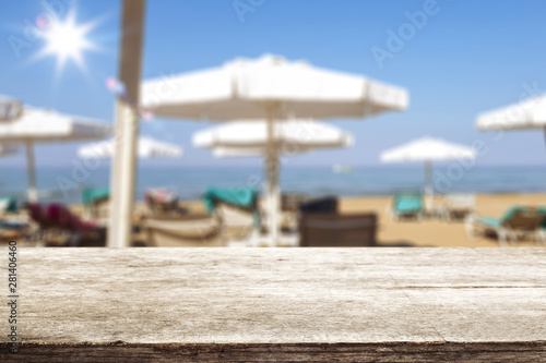 Beach background with lounge chairs and umbrellas and table top for advertising products and decoration. Sunny summer day.