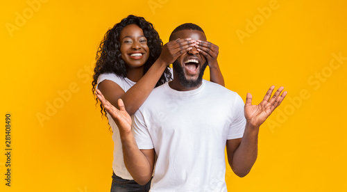 Cheerful afro girl closing her boyfriend eyes from behind