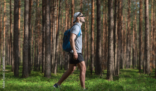 A man with a backpack walking in a beautiful forest.