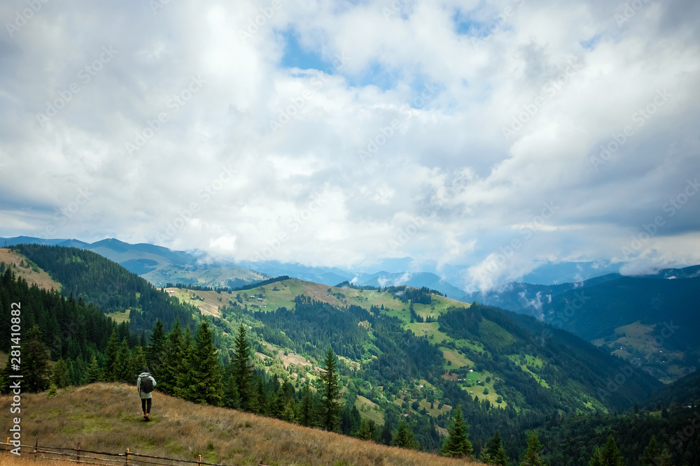 Creative background, A male tourist walks through a mountainous area with a backpack. The concept of active tourism, recreation, the Carpathians. Copy space