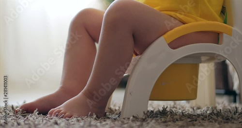Children's legs hanging down from a chamber-pot. Baby boy sitting on potty. Funny Child sitting on chamberpot.