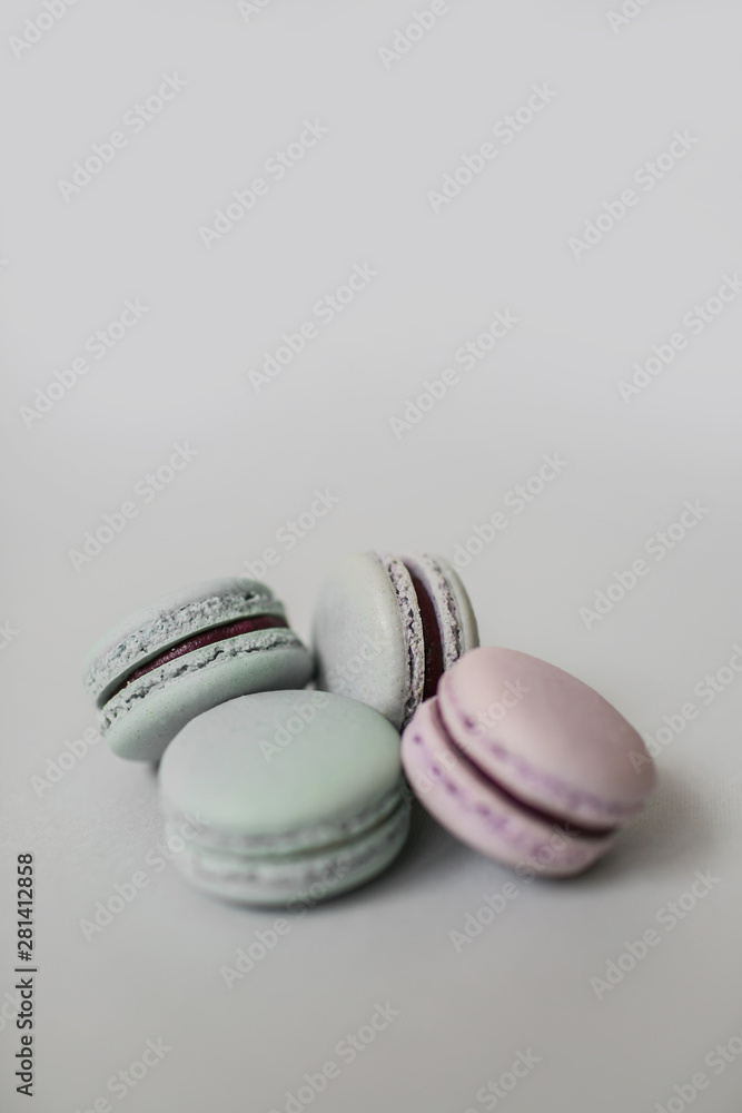 Fototapeta premium Top view of a pile of sweet macaroon biscuits of pastel color lying on light grey background. Copy space.