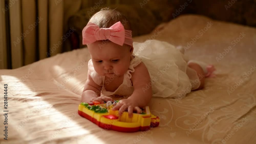 little baby playing with toy at home. happy child girl laying on bed in nursery little baby playing with toy at home. happy child girl laying on bed in nursery