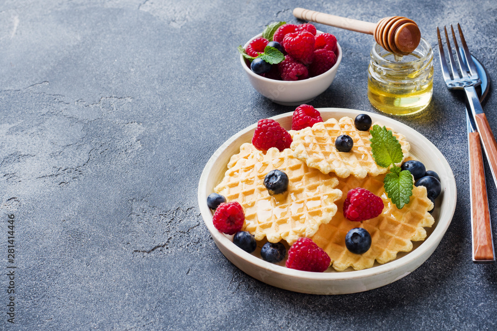 Corrugated waffle cookies with fresh raspberries and blueberries on a dark concrete background. Copy space. Corrugated waffle cookies with fresh raspberries and blueberries on a dark concrete background. Copy space.