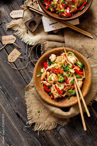 homemade tasty wok noodles with fried chicken fillet, broccoli, red ball pepper, green onion, sesame