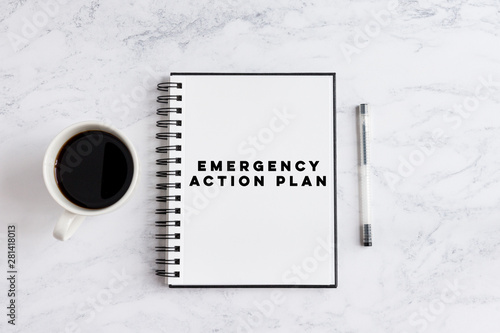 Emergency Action Plan writing on notebook. Notebook on desk with coffee cup and a pen.