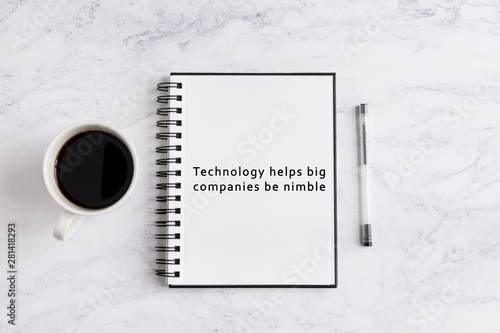 Technology helps big companies be nimble writing on notebook. Notebook on desk with coffee cup and a pen.