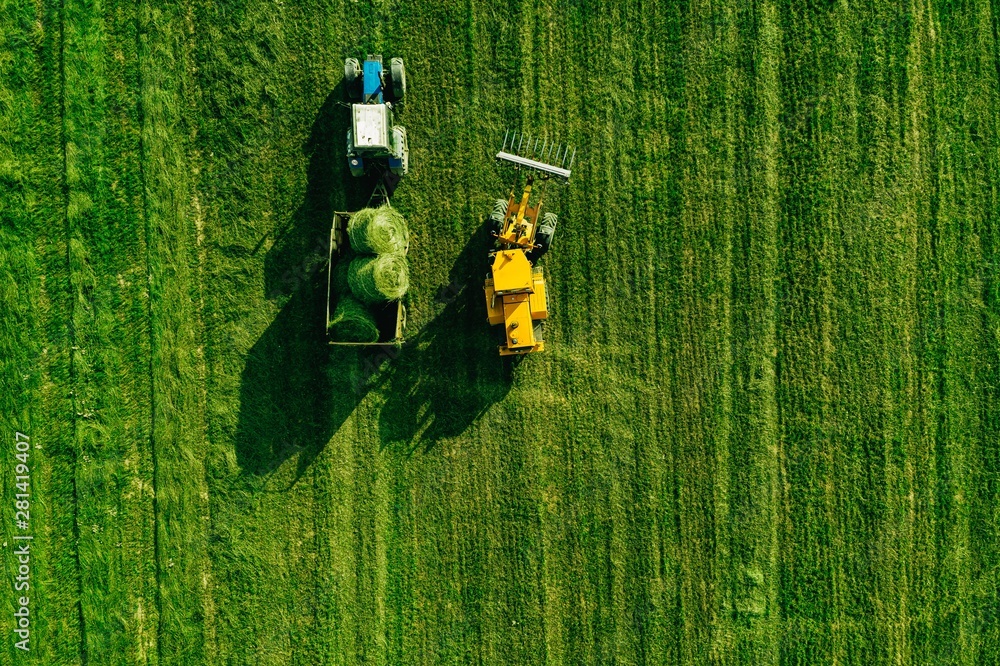 Aerial view of harvest field with tractor moving hay bale