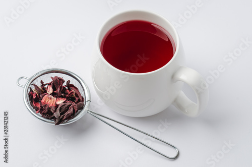 red hibiscus tea in a white mug and dry blossom isolated on white background, selective focus