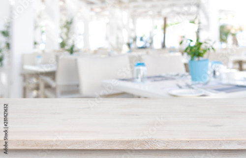 Defocused resort restaurant background with wooden table top in front © didecs