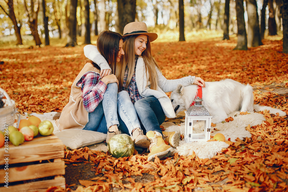 Fototapeta premium Beautiful girls in a park. Cute ladies in a stylish clothes. Friends with cute dog