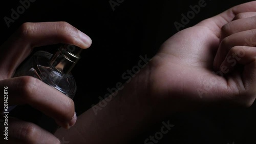 A girl spraying scent / perfume on her wrist to smell the fragrance .  photo