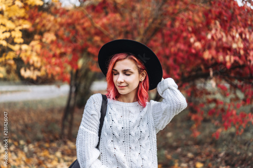 Pretty girl with red hair and hat walking in the park, autumn time.