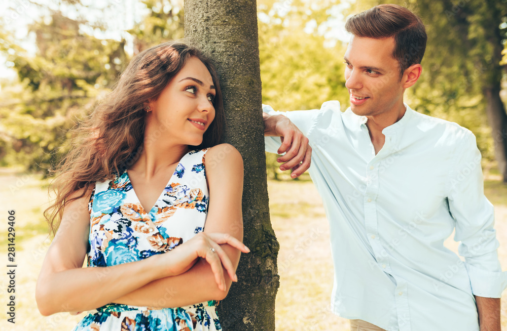 Young couple looking to each other with love. Portrait of man and woman posing outdoors in the park.
