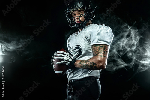 Tableau sur toile American football sportsman player in helmet on black background with smoke