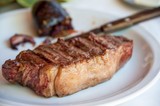Traditional delicious grilled argentine barbecue steak on white plate close up with blurred background. Selective focus.