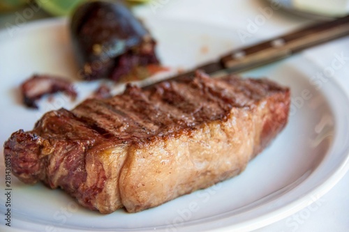 Traditional delicious grilled argentine barbecue steak on white plate close up with blurred background. Selective focus.