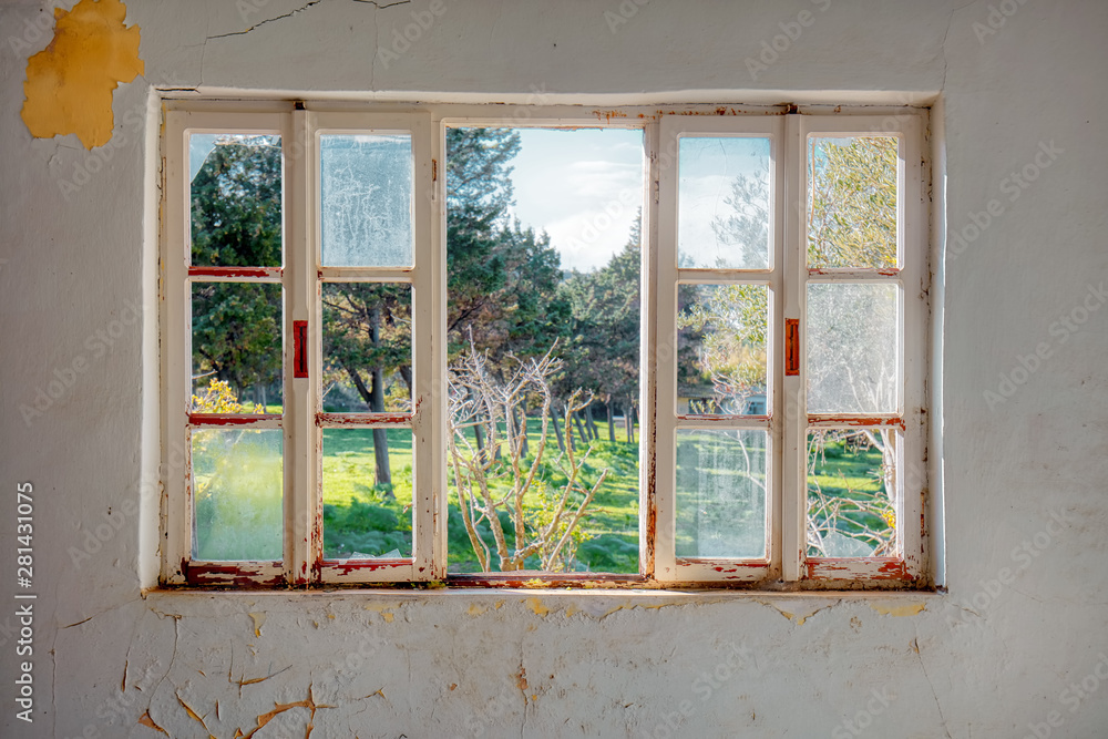 Vintage wooden window frame with broken glass looking through a green meadow field. of an Interior of a desolated house with dirty cracked wall. - obrazy, fototapety, plakaty 