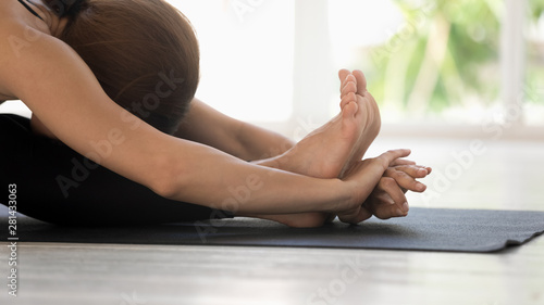 Woman practicing seated forward bend pose on mat closeup view