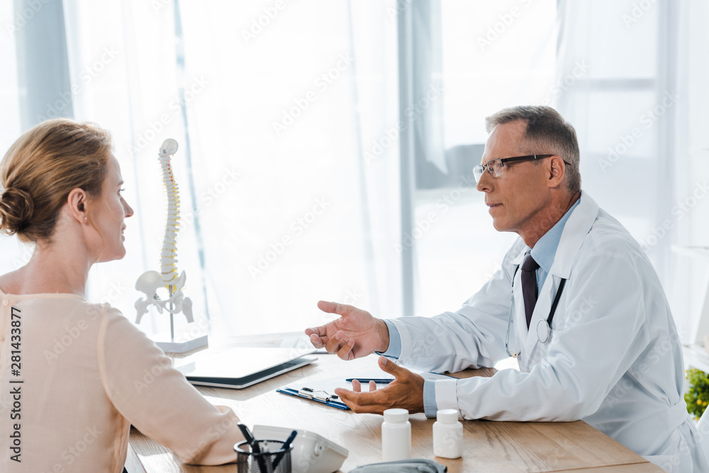 doctor in glasses looking at woman while sitting near table doctor in glasses looking at woman while sitting near table
