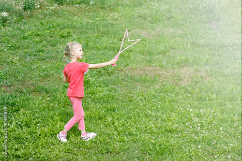 little girl, blonde, playing in the meadow, and blows a bubble.