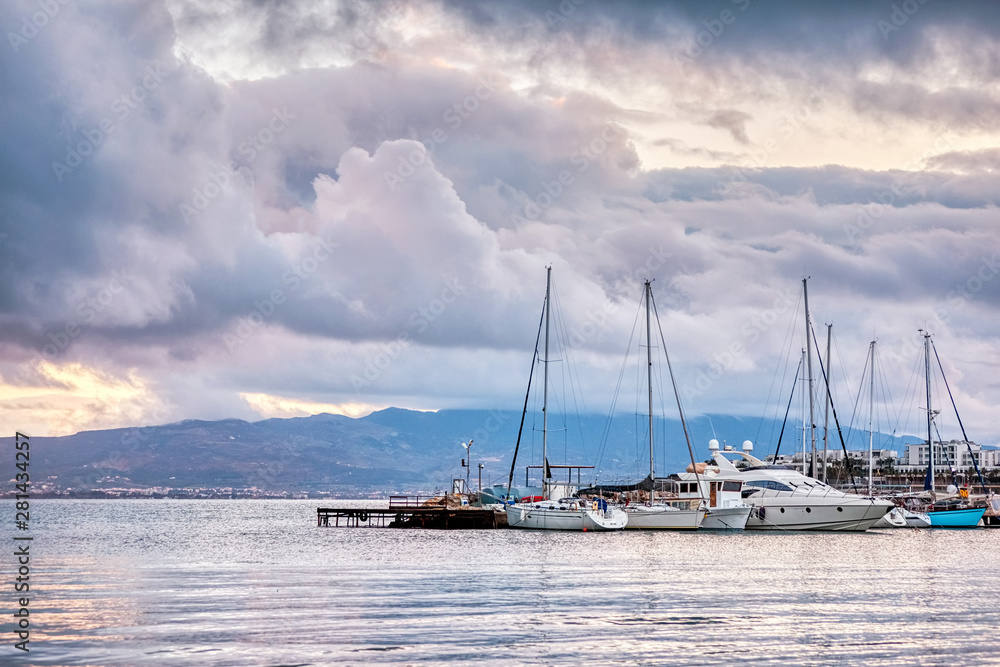 Yachts and motorboats docked in sea port on a cool and cloudy day. Beautiful cloudscape and seascape view in Akyarlar harbor, Bodrum, Turkey.