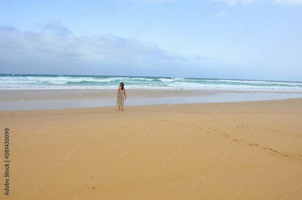 Girl Wearing a Dress Walking by a Long Sand Beach in Fuerteventura, Canary Islands Girl Wearing a Dress Walking by a Long Sand Beach in Fuerteventura, Canary Islands
