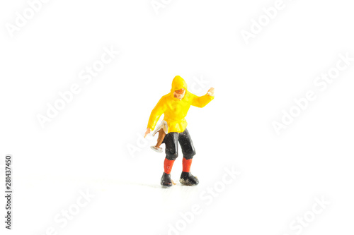 Miniature Person wearing a yellow rain jacket standing on a White Isolated Background © Sean